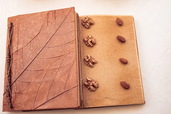 Top view, book made of autumnal leaves, on one page nuts and almonds, recyclable material. Introvert and minimalist lifestyle concept - Image