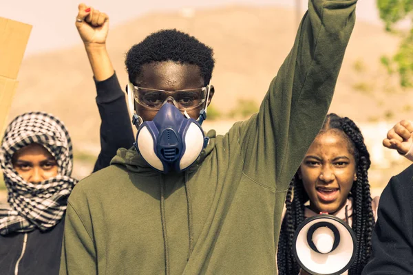 ガスマスクを持つ若い黒人男性の肖像画は 2人の若い異なる民族の女性の後ろに 黒の生活問題 — ストック写真