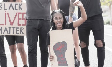 Afroamerikalı kız elinde ırkçılık işareti yok, aktivistler insan hakları sloganı atıyor. Bir grup insan dışarıda hakları için protesto yapıyor. Resim