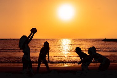 Gün batımında deniz kıyısında voleybol oynayan mutlu kızlar. Gençler yaz tatilinde eğleniyor. Seyahat, parti ve arkadaşlık konsepti. Resim