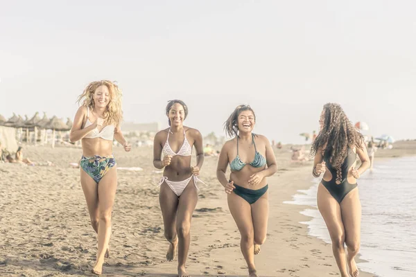 Kumsalda mutlu genç kızlar. Birlikte koşup eğleniyoruz. Yaz ve tatil konsepti.
