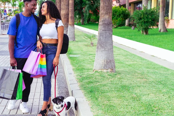 Güzel, genç ve sevgi dolu bir çift alışveriş torbaları taşıyor ve birlikte eğleniyorlar. Genç bir çift ve köpek dışarıda yürüyor..