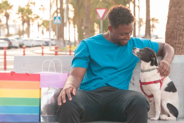 Parktaki bankta oturup köpeğini arayan mutlu bir adam. Gençler alışverişten sonra dinleniyor. Rahatla, satın al ve evcil hayvan konsepti.