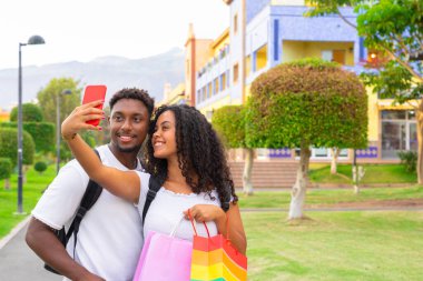 Parlak anları yakalıyorum. Neşeli genç çift kamerada selfie çekiyor. Yeni teknoloji trendleri ve arkadaşlık kavramı.