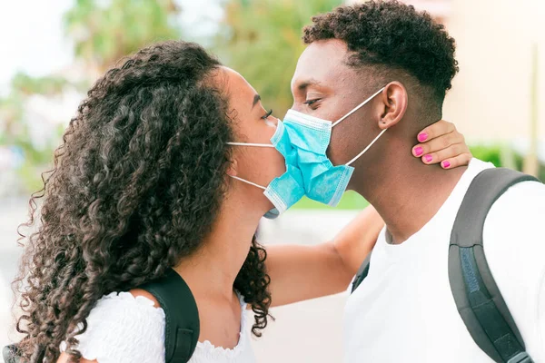 Genç çift Coronavirus salgını sırasında yüz maskesi takarken öpüşüyor. İlişki ve Covid 19 konsepti.