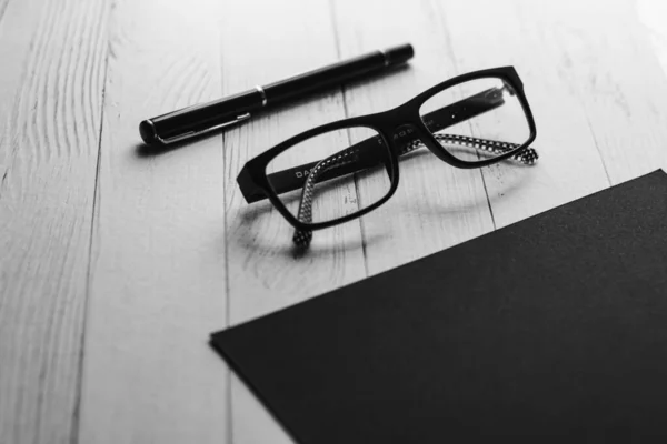 Bir gözlük ve siyah arka planda bir kalem. İş konsepti. Metin için kara liste