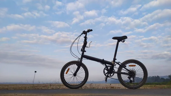 Mavi gökyüzü ve bulut arkaplanlı bir kumsalda bisiklet.