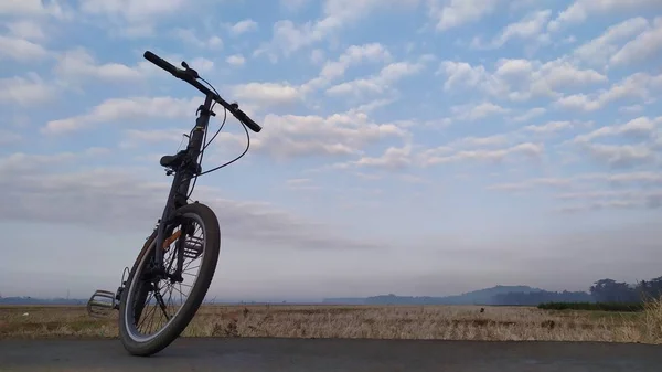 Mavi gökyüzü ve bulut arkaplanlı bir kumsalda bisiklet.