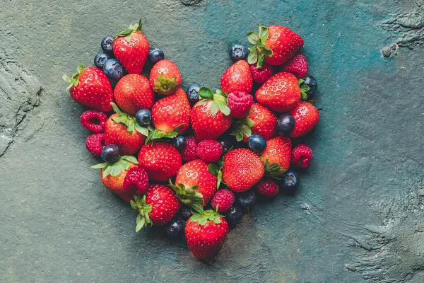 Forest fruits in heart shape on dark background Conceptual of healthy food, vegetarianism, veganism, health