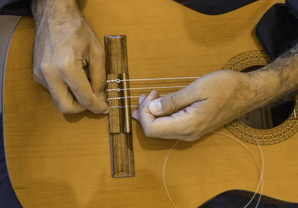 Male hands changing the strings of a classical guitar Luthier putting nylon strings on a Spanish classical guitar