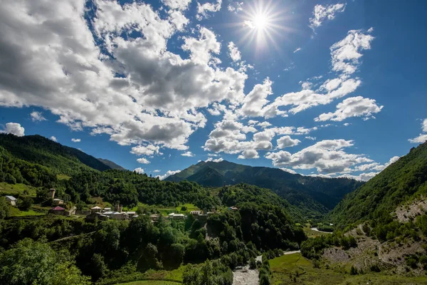 small apartment buildings high in the Caucasus mountains among the forest, blue sky with white clouds