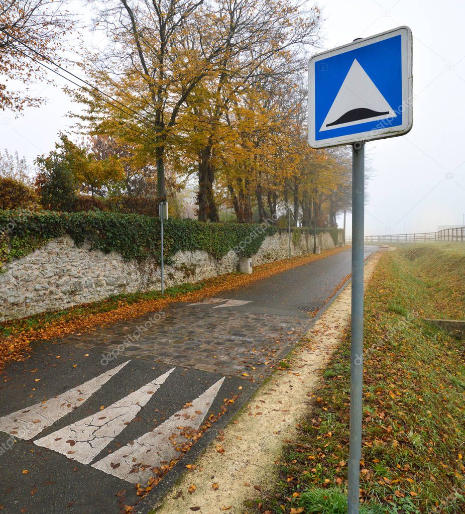 Speed bump or speed humps, in the road, in a village. Autumn day with fog