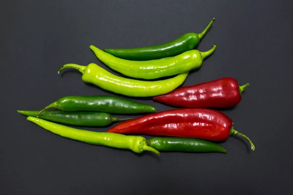 Top view of red and green peppers on dark grey background