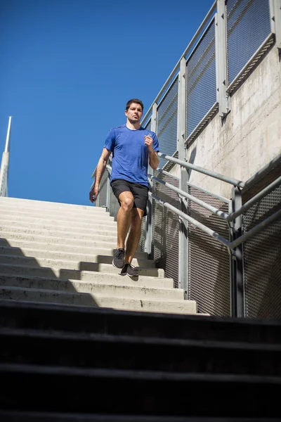 Male athlete exercising running down the stairway