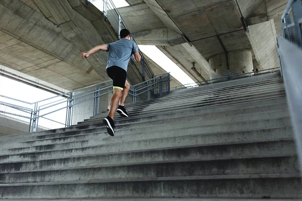 Side view of active fit man jogging by stairs