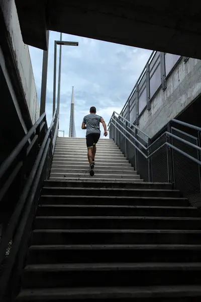Rear view of fit male runner climbing up stairs