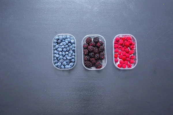 Fresh blueberries, blackberries and raspbarrys organized against black background