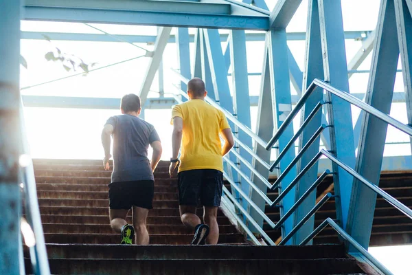 Two professional male athletes running on the bridge