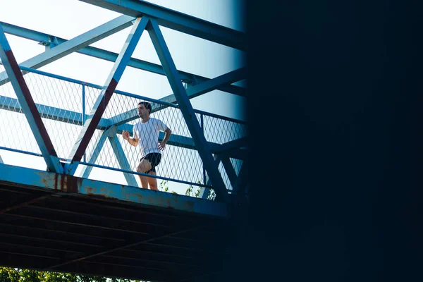 Professional male athlete running on the bridge