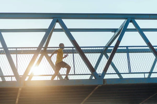 Professional male athlete running on the bridge