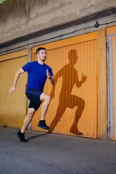 Professional male athlete running in front of garage