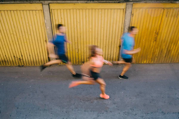 Professional athletes running down alleyway, blurred motion