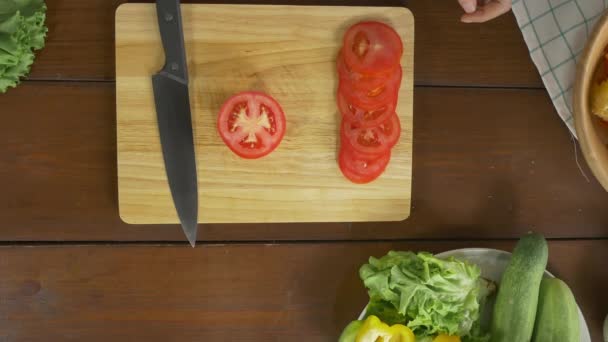 女性チーフ サラダ健康的な料理を作る 台所でまな板の上にトマトをまな板の上から見る — ストック動画