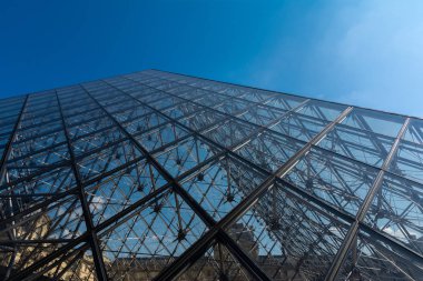 Louvre Müzesi 'nin kristal piramidi mavi güneşli gökyüzünün altında