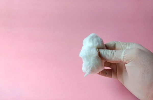 Ruka s bílou rukavicí s bavlnou na růžovém pozadí. lékařská koncepce — Stock fotografie