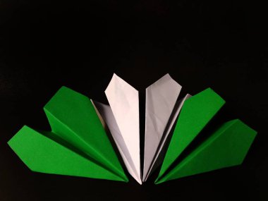 Siyah arka planda yeşil ve beyaz kağıt uçaklar. eğlenceli konsept