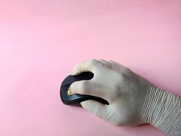 Mano con guante de látex blanco usando un ratón de computadora en un laboratorio sobre fondo rosa. concepto médico —  Fotos de Stock