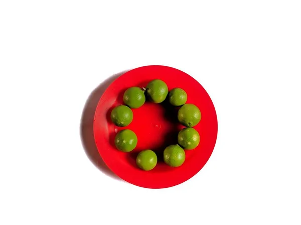 Limones Ecológicos Verdes Con Plato Rojo Sobre Fondo Blanco Concepto — Foto de Stock