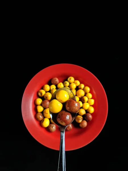 Yellow Brown Nances Red Plate Spoon Black Background Typical Fruit — Stock Photo, Image