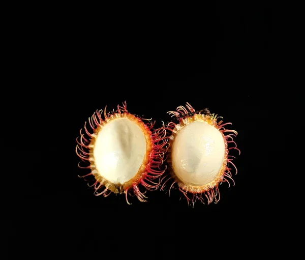 Rambutan fruit cut in half with black background. exotic fruits from Asia