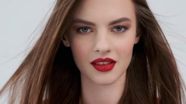 Kırmızı dudaklı güzel bir genç kadının portresi. Uzun düz saçlı, çekici bir kız. Şehvetli manken. Seksi, beyaz bir kızın yakın plan yüzü gibi. 4K görüntü. Yavaş çekim.