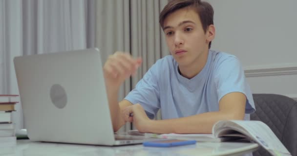 十几岁的男孩在家里上学校的课 学生写作业 孩子们学习 男孩使用笔记本电脑 学生用笔在笔记本上写字 — 图库视频影像