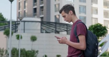 Parkta cep telefonu kullanan bir genç. Dışarıda cep telefonu kullanan genç bir adam. Cep telefonu olan genç bir çocuk. Şehir manzarası. Yakışıklı adam akıllı telefon kullanıyor. 4 bin. Gerçek zamanlı..