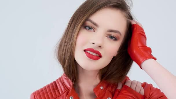 一个红唇美女的画像 穿着红色皮夹克的时髦女孩 在工作室摆姿势 性感时尚模特 一个令人惊叹的高加索女孩的脸 4K镜头 慢动作 — 图库视频影像