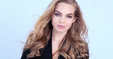 Uzun saçlı güzel sarışın kadın. Moda modeli kameraya bakıyor. Kafkasyalı bir kızın çarpıcı yüzü. Güzel mavi gözlü seksi bir manken. Ağır çekim. Güzellik konsepti. 4k görüntü.