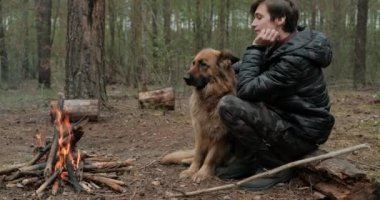 Genç, bir köpekle ateşin yanında oturuyor. Genç adam şöminenin yanında bir çoban köpeğiyle dinleniyor. Bir sonbahar akşamında evcil hayvanı olan biri..