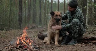 Büyük köpekli bir adam ormanda ateşin başında oturur. İnsan sonbaharda ateşe bakar ve doğada köpeğine dokunur. Yalnız gezgin orman yangınında Alman çobanıyla dinleniyor..