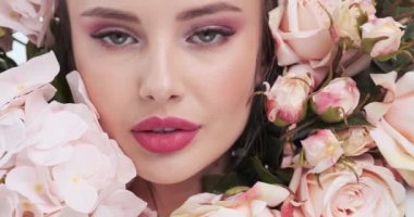 Face with flowers. Beautiful caucasian woman with fresh skin. Closeup female face with flowers. Beauty concept. Skin care. Young girl with natural makeup. 4k. Slow motion