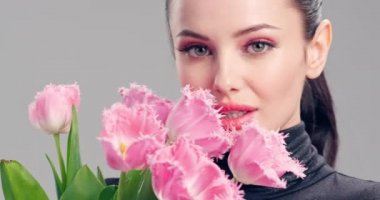 Çiçekli güzel beyaz kız. Pembe lalelerden oluşan büyük buket çiçekleriyle göz kamaştırıcı esmer kız. Temiz ciltli, genç ve güzel bir kadının yakından çekilmiş yüzü. Parlak makyajlı kadın. 