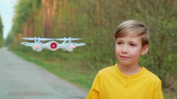 子供は屋外でドローンを起動します 少年は自然界で四人組で遊ぶ 白人の少年は公園で無人機を制御することを学んでいる スローモーションビデオ — ストック動画