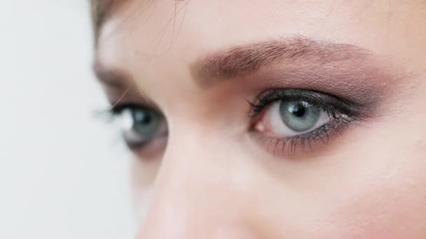 クローズアップ 明るいダークメイクの女性の目 青い目の女性の顔のマクロショット 長い黒いまつ毛を持つ女性の目 角度の低いビュー 化粧品のコンセプト — ストック動画