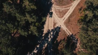 İHA 'dan gelen hava görüntüsü, bir ralli aracını takip ediyor. Fast Buggy büyük toz bulutlarıyla gidiyor. İnsansız hava aracından orman yolundaki ırka üstten görüntü.