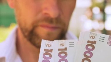Sinematik çekim: Erkekler Ukrayna 'nın parasının 1000 hryvnia değerinde olduğunu düşünürler. Kişi banknotları sayar. Adam bir tomar para sayıyor. Paralı insan elleri.