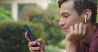 Parkta cep telefonu kullanan bir genç. Açık havada cep telefonu kullanan gülümseyen genç bir adam. Cep telefonu olan mutlu bir çocuk. Şehir manzarası. Yakışıklı adam akıllı telefon kullanıyor. 4 bin. Gerçek zamanlı..