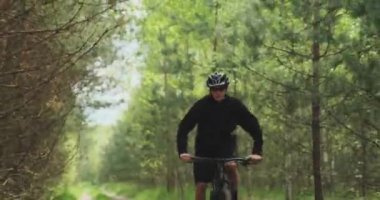 Orman yolunda bisiklet süren genç bir adam. Dağ bisikleti süren bir genç ormanda geziyor. Bisiklet kasklı bir adam MTB bisikleti sürüyor..