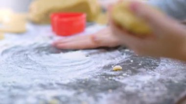 Çocuğun elleri bir parça hamur tutuyor ve sıkıyor, yakın görüş. Çocuk mutfakta yemek pişiriyor. 8 yaşındaki çocuk evde yemek pişiriyor. Yavaş çekim 4K görüntüsü. Çocuk elindeki hamuru karıştırıyor..  